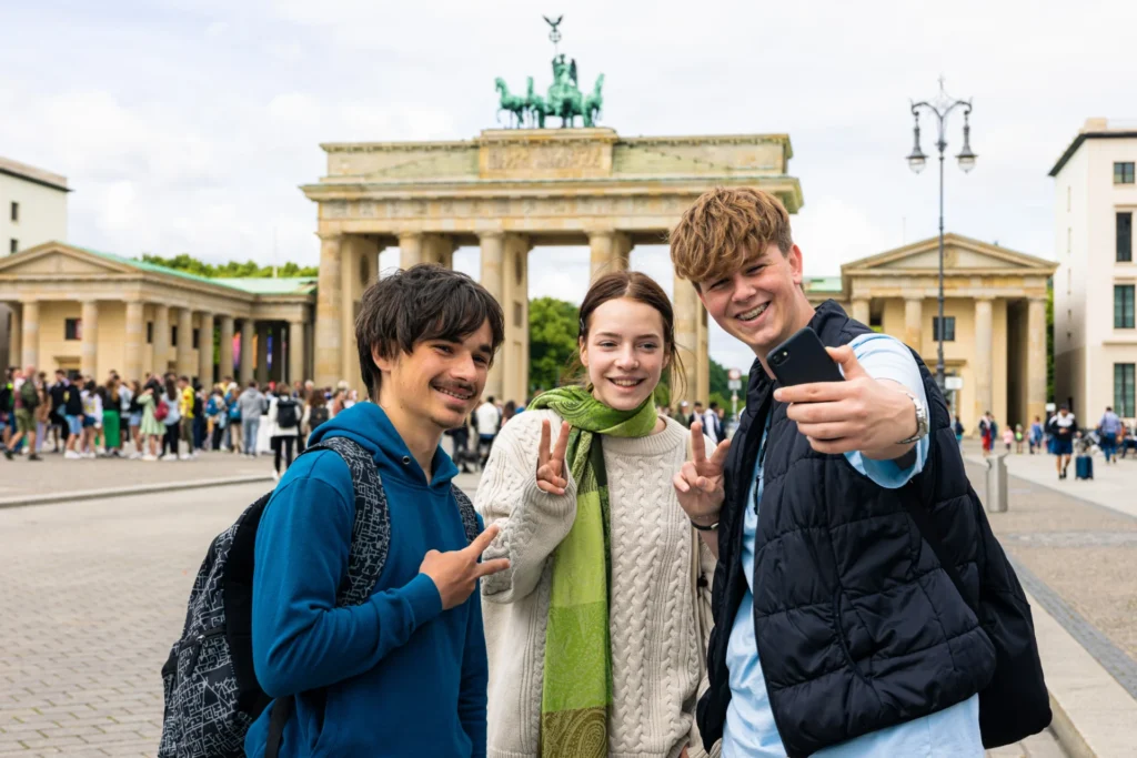 Schülergruppe macht Selfie auf einer Klassenfahrt in Berlin vor dem Brandenburger Tor