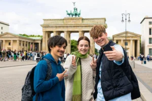 Schülergruppe macht Selfie auf einer Klassenfahrt in Berlin vor dem Brandenburger Tor